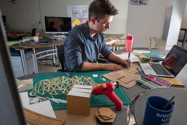 Student works on interior design on his laptop