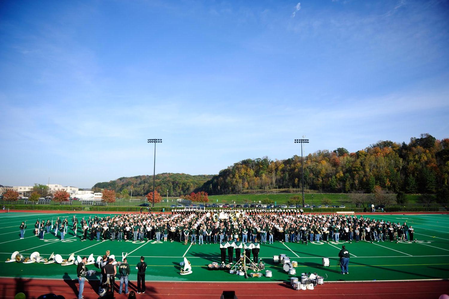 Marching 110 alumni play their instruments on the field